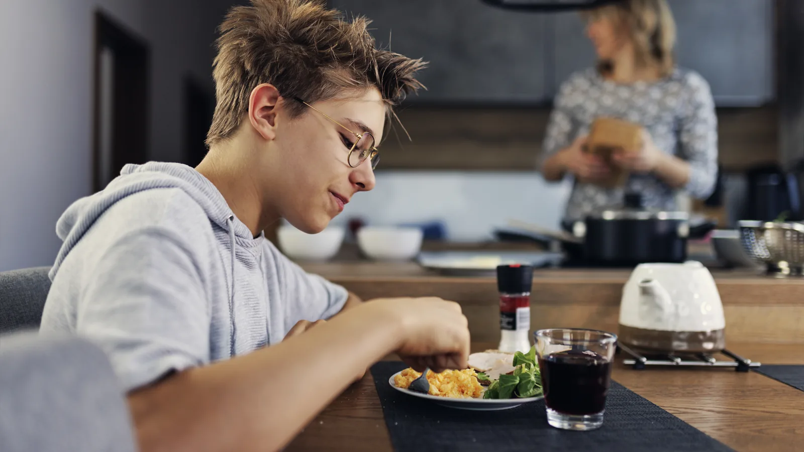 Teen boy eating breakfast while a parent stands nearby for an ARFID family support guide