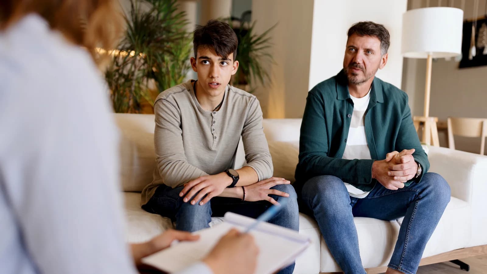 Father and son speaking with a psychotherapist during family therapy