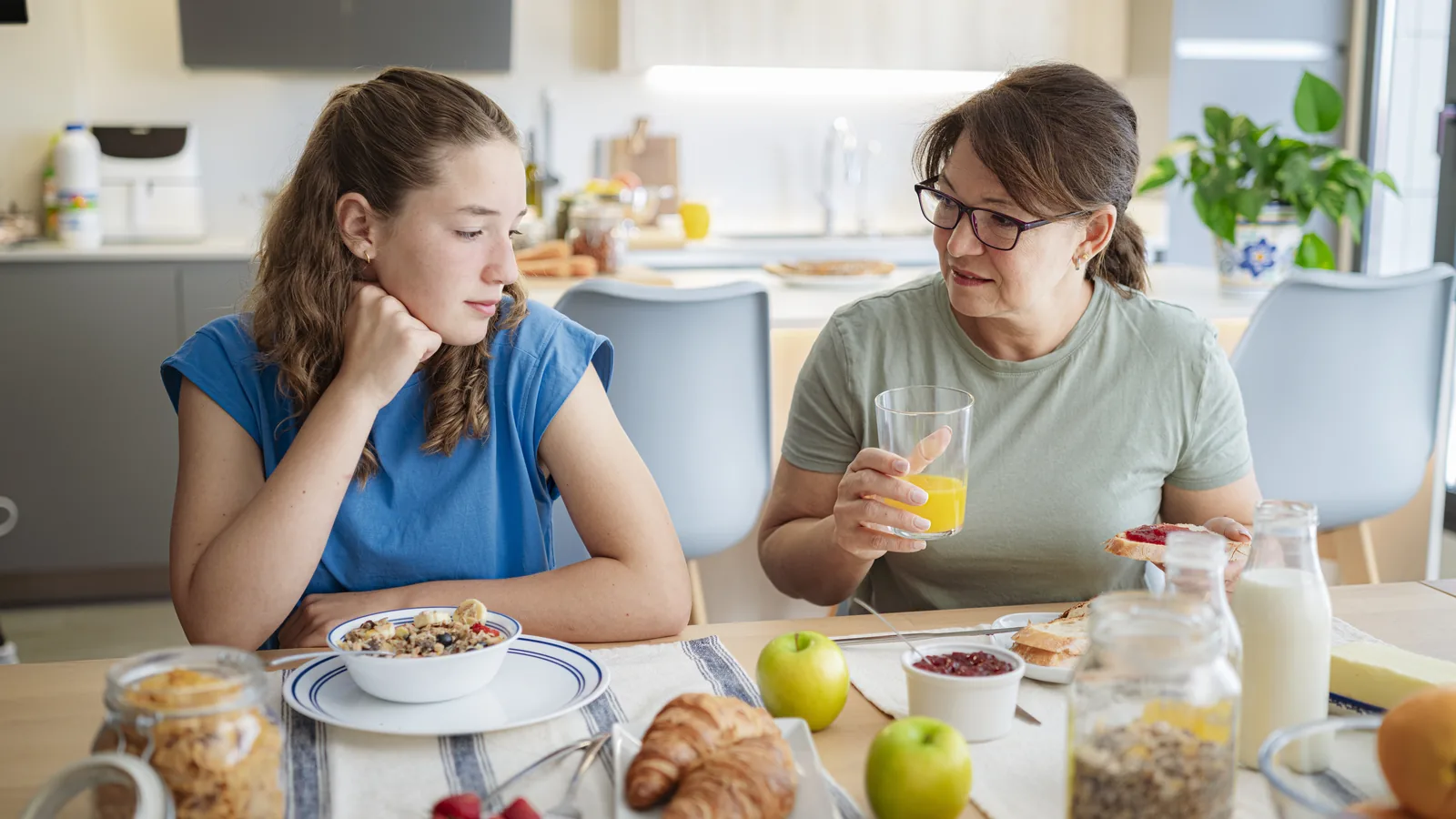 Mother and distraught teen daughter sitting together at breakfast for an eating disorder conversation guide