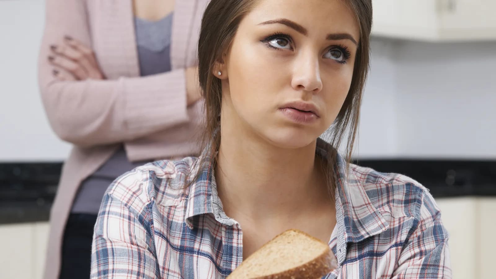 Worried mother speaking with teen daughter at breakfast about food and body image concerns