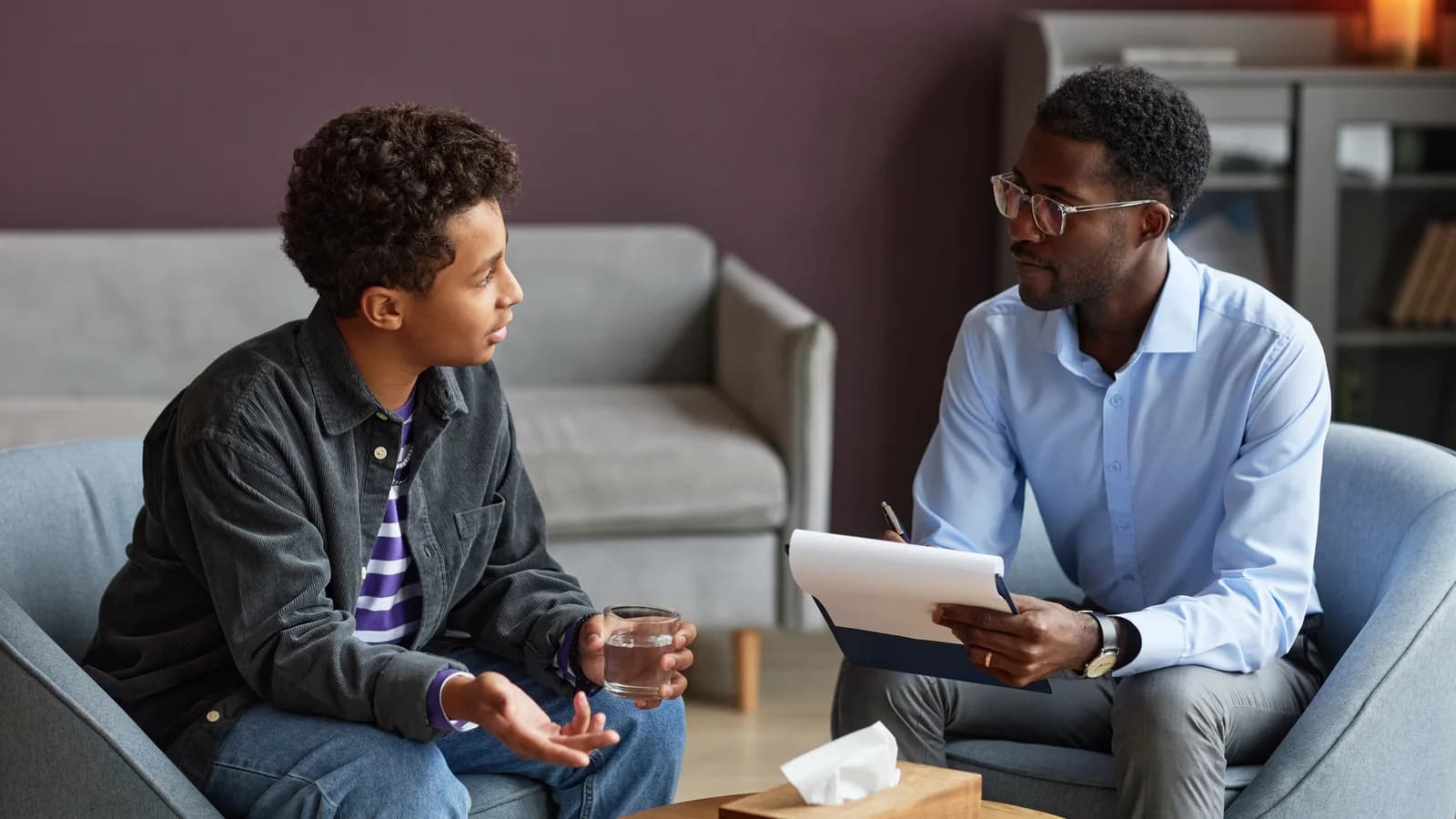 Teen boy talking with an adolescent psychologist before starting treatment