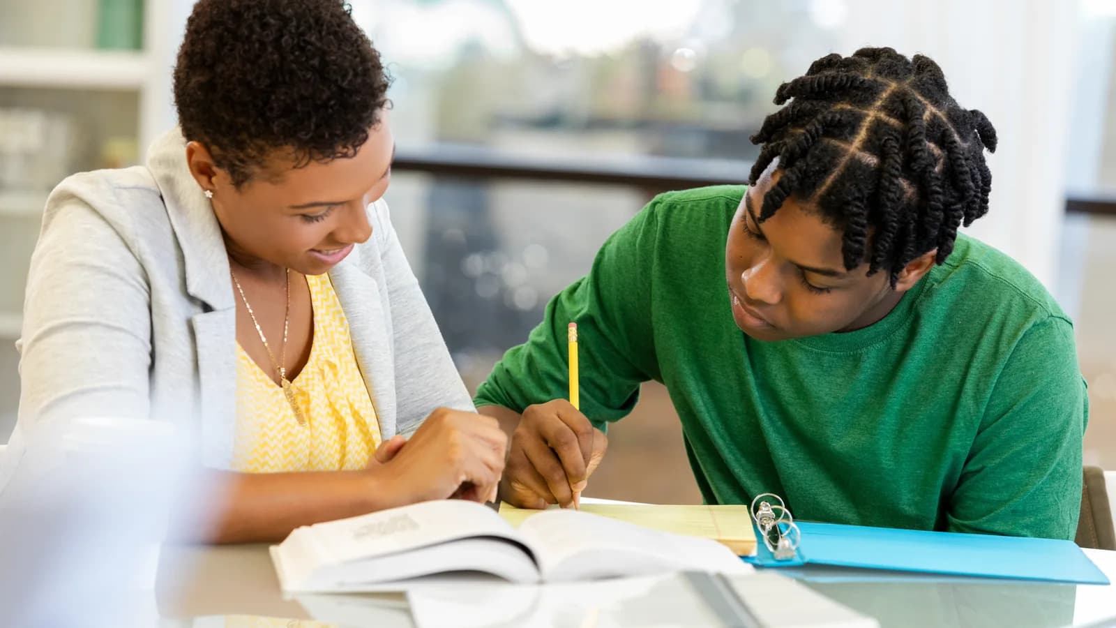 Young man doing schoolwork with adult support during treatment planning