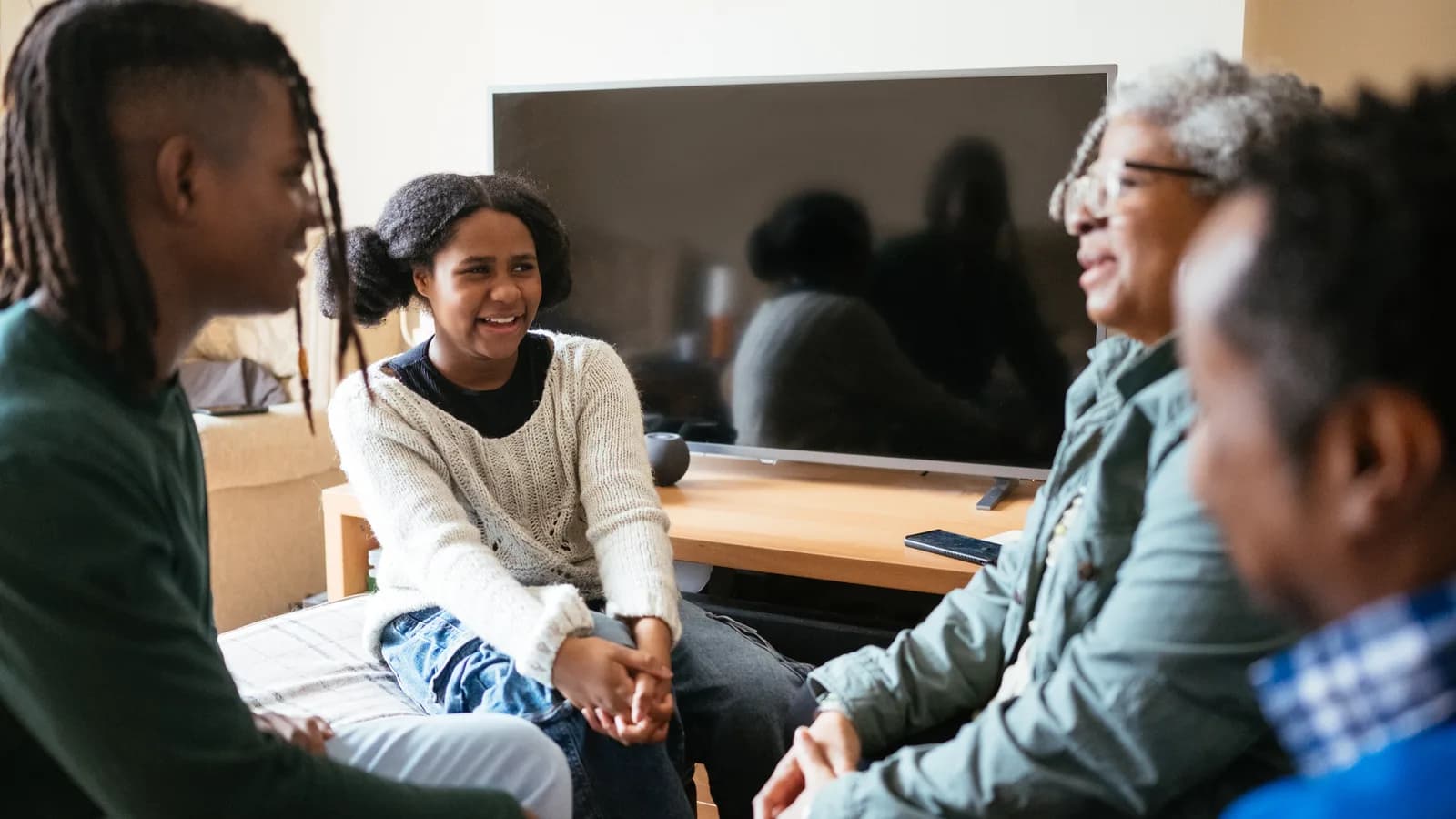 Family with two teenage children in a living room for a guide about siblings and teen mental health treatment