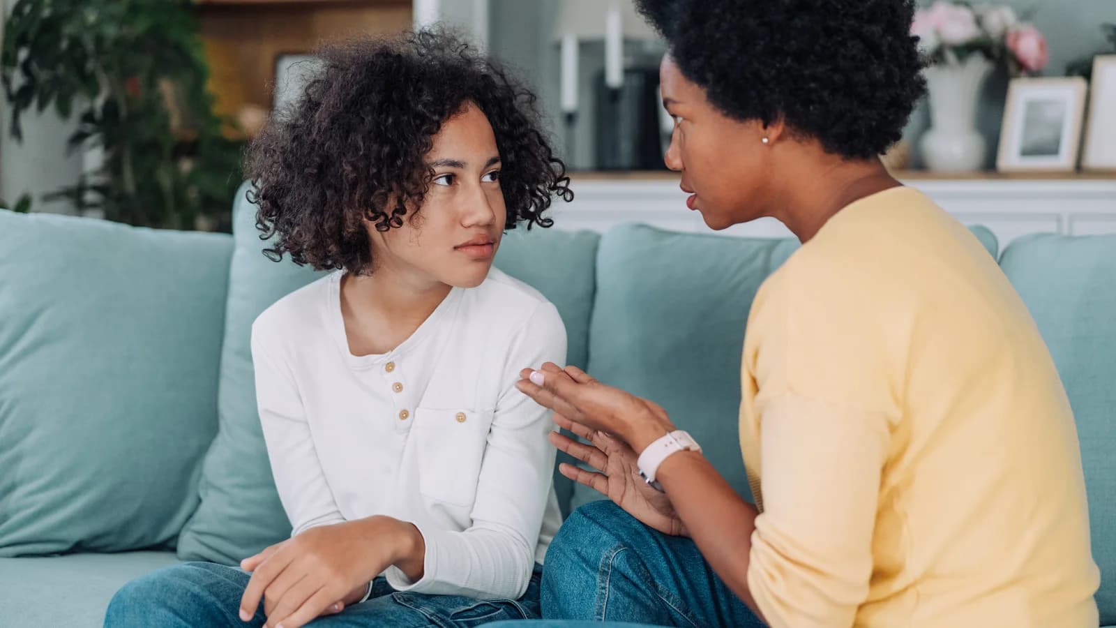 Mother sitting with anxious teenage daughter during a supportive conversation at home
