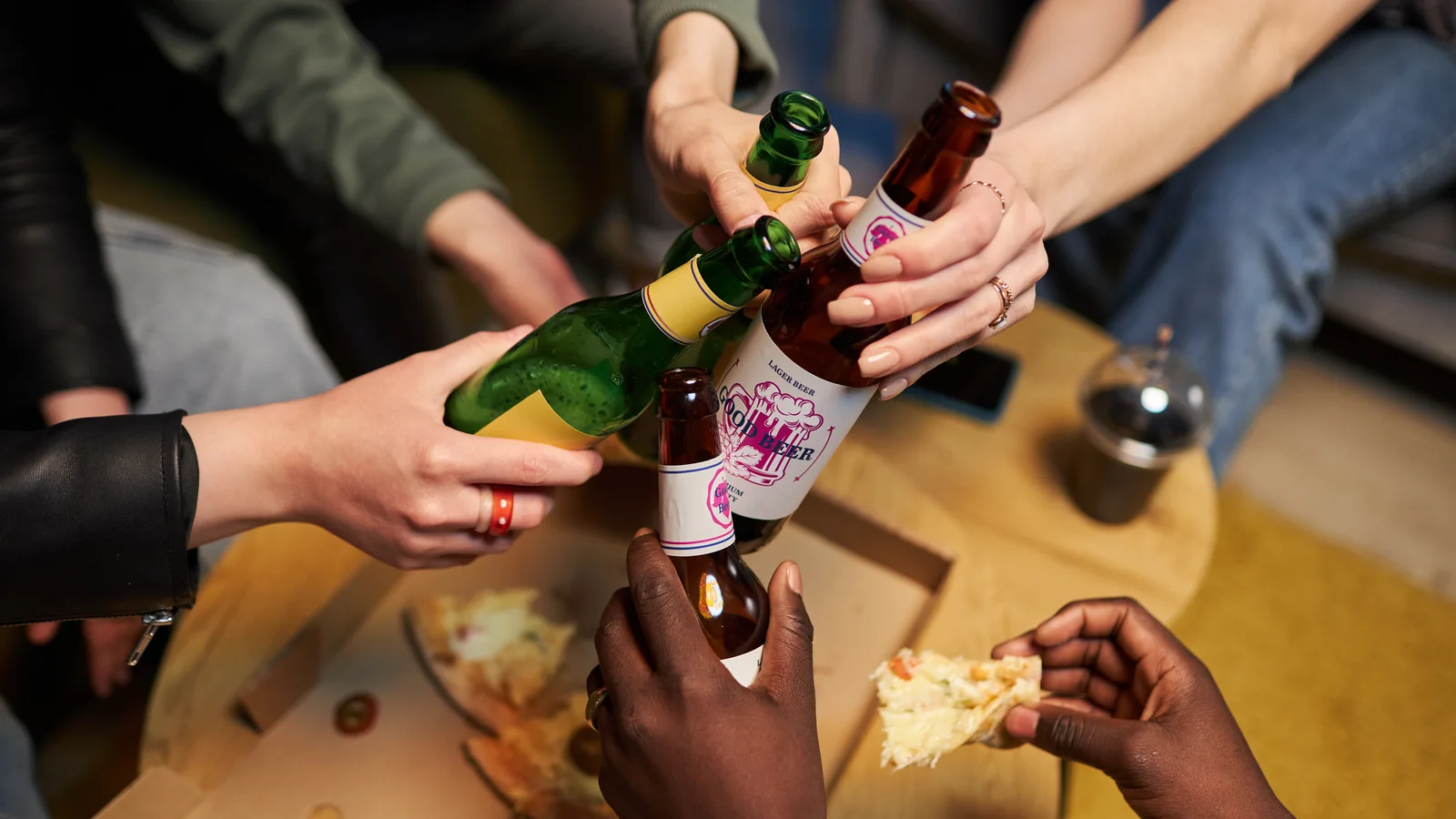 Hands clinking beer bottles at a party for a parent guide about teen alcohol use