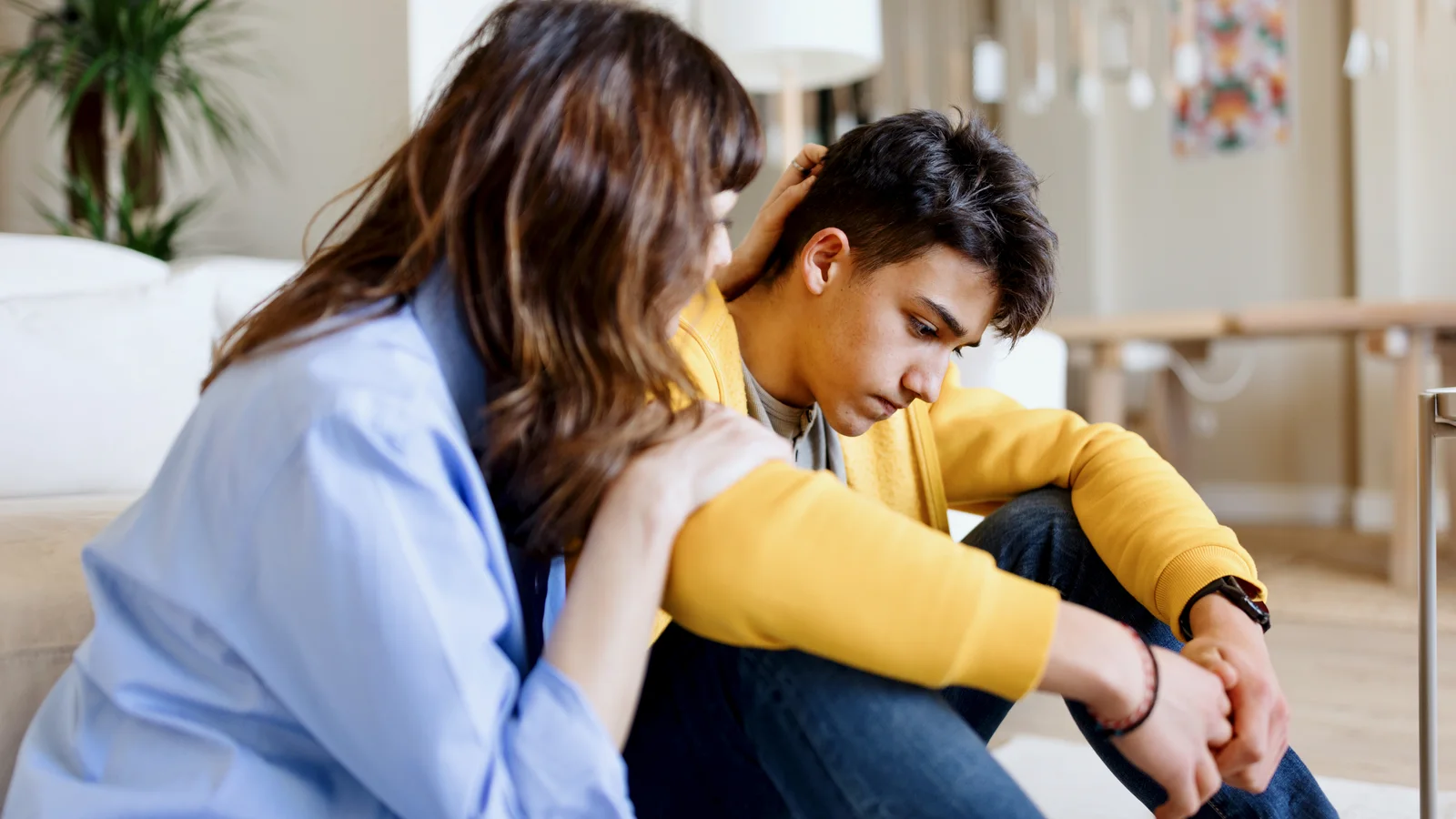 Worried teenage son talking with his mother about stress and anxiety at home