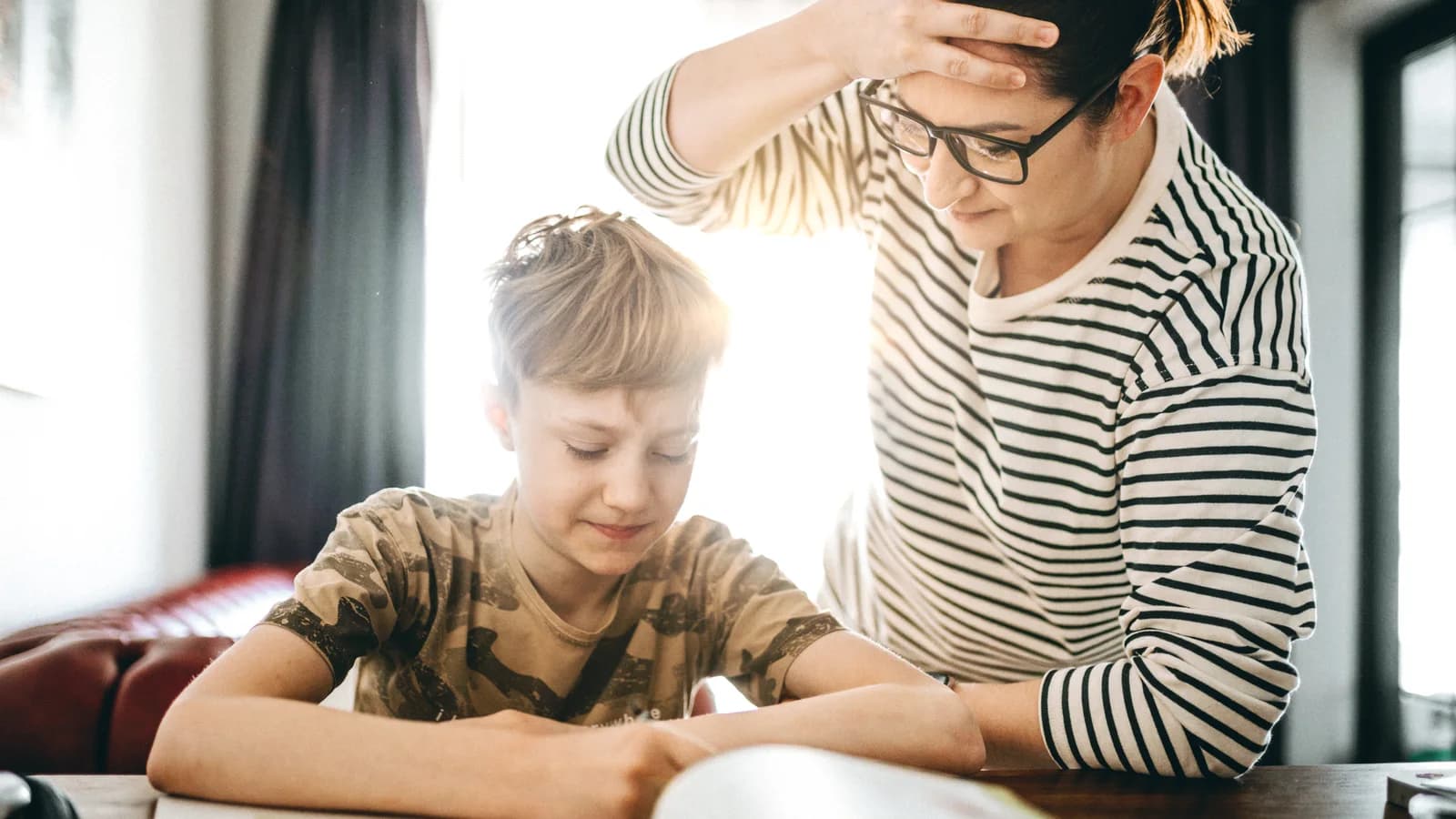 Teen boy struggling with homework while his mother stands nearby for an anxiety and stress guide