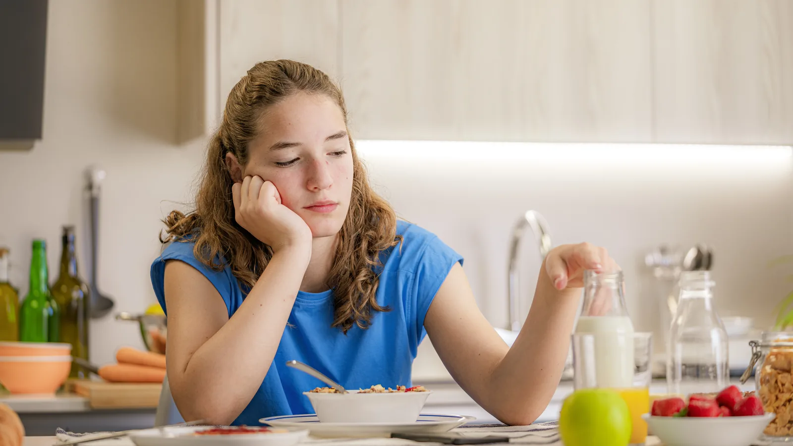 Distressed teen girl at a kitchen table for a binge eating disorder parent guide