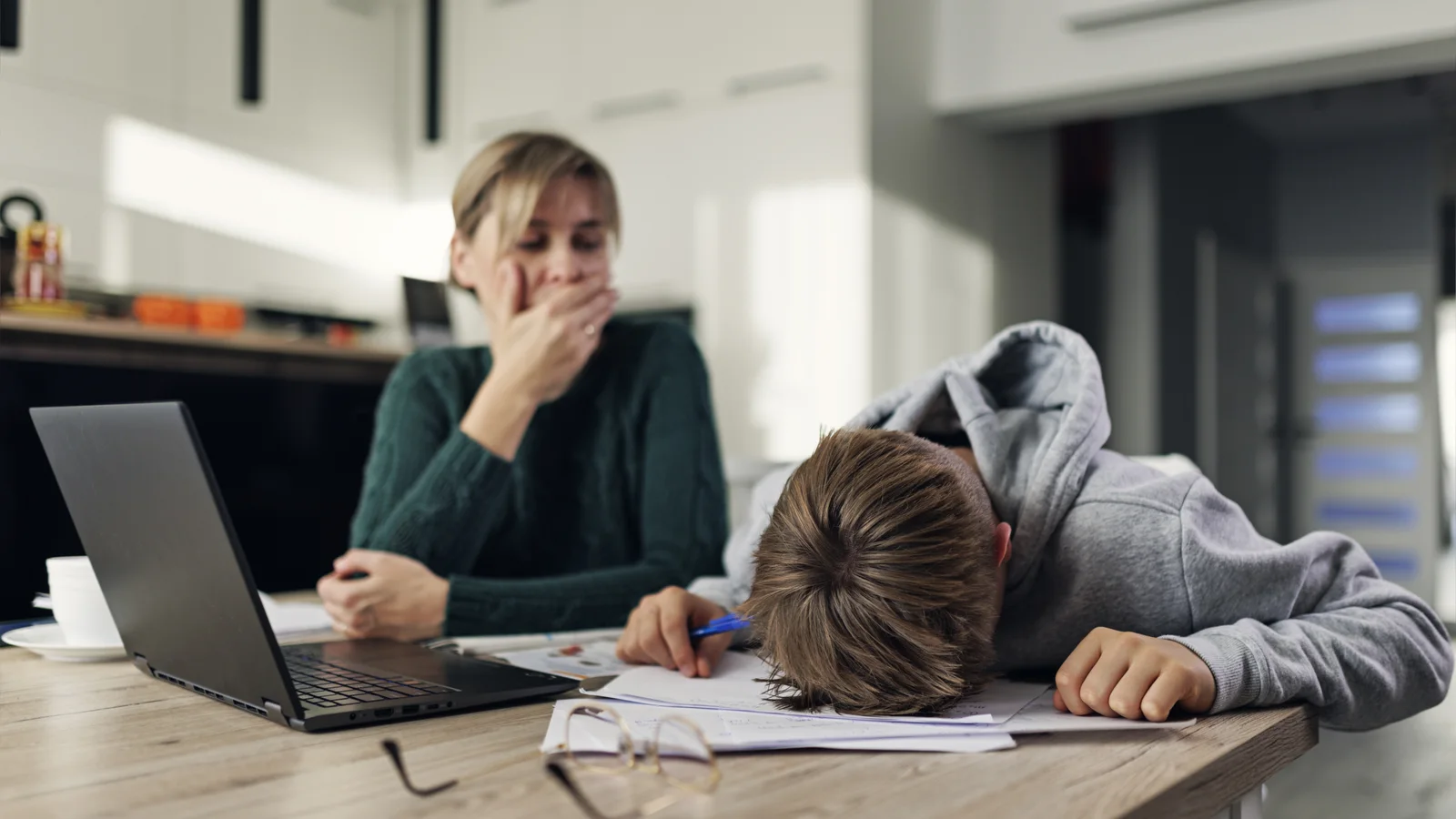 Mother helping a frustrated teenage son with difficult homework for a teen depression guide