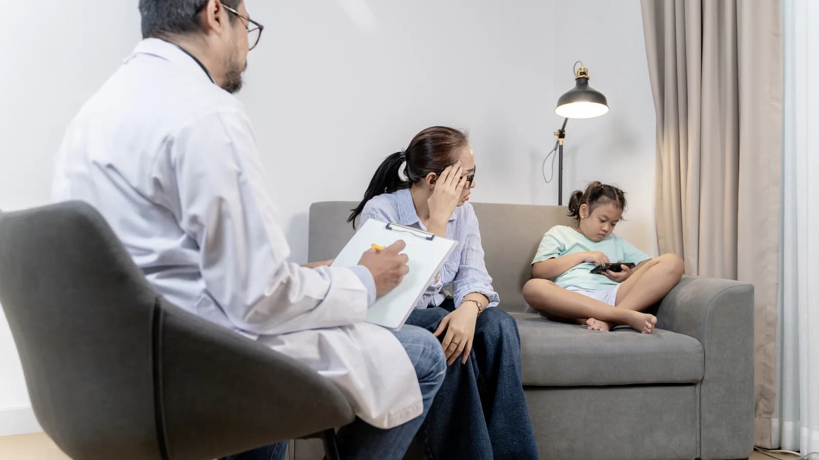 Mother consulting a clinician while a teen sits nearby during a behavioral health appointment