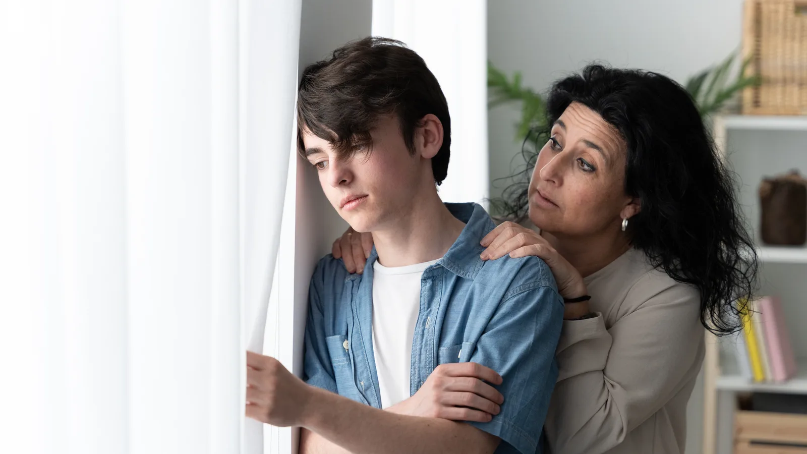 Mother comforting a sad teenage son at home for a guide about teen grief and depression support