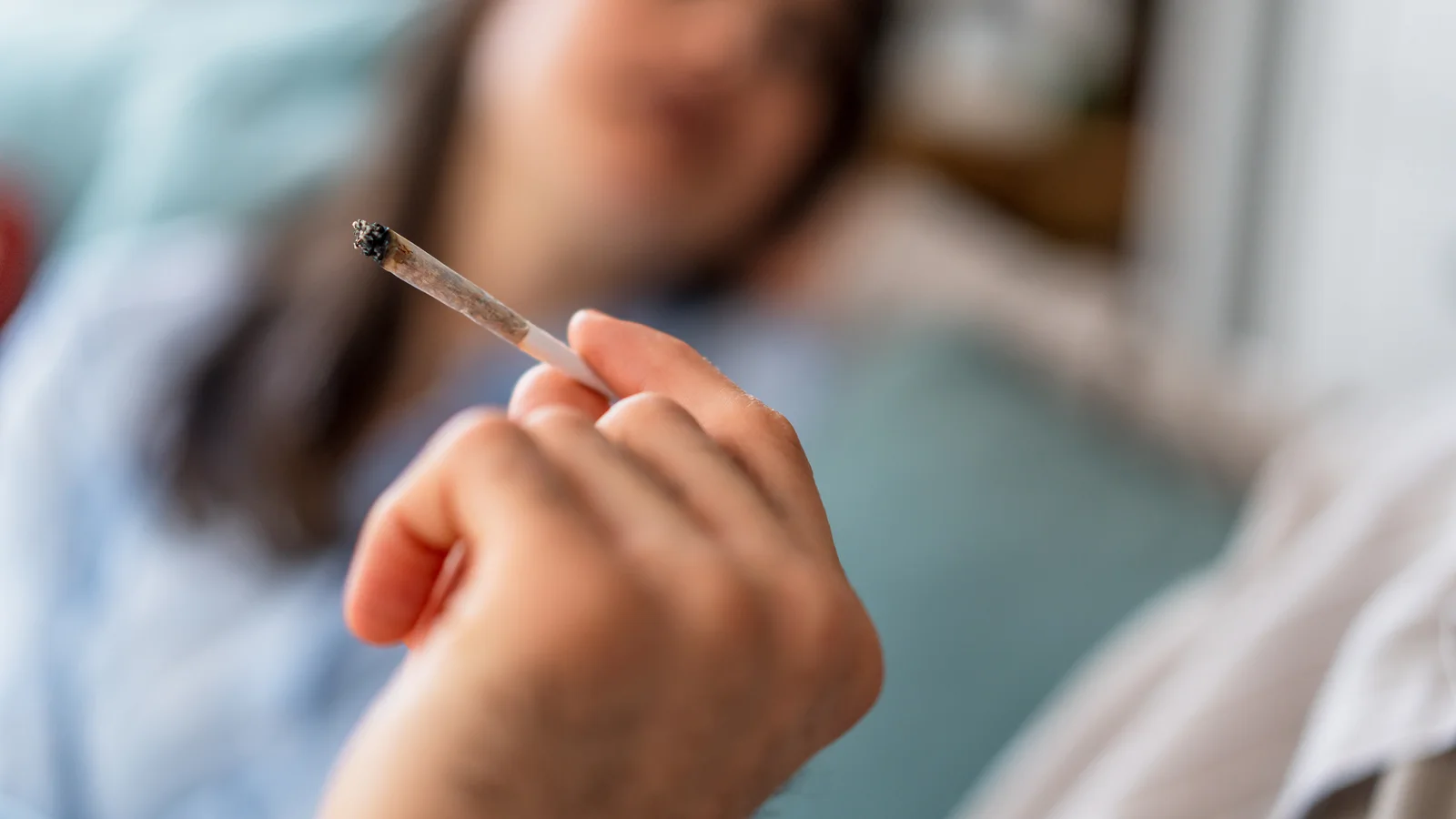 Hand holding a marijuana joint for a guide about teen cannabis use and self-medication