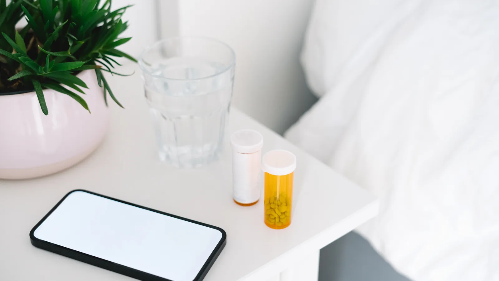 Prescription pill bottle and phone on a bedside table for a teen opioid misuse guide
