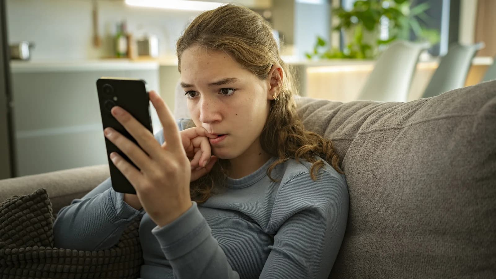 Nervous teen looking at a phone for a guide about social anxiety and peer stress
