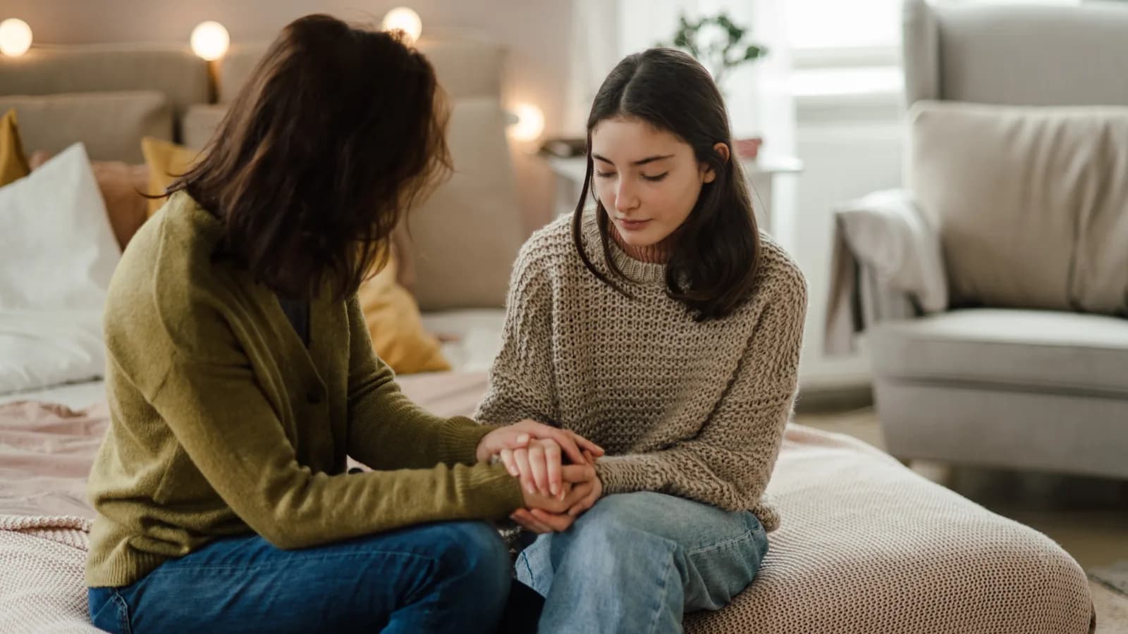 Mother holding her teen daughter's hands during a serious mental health conversation