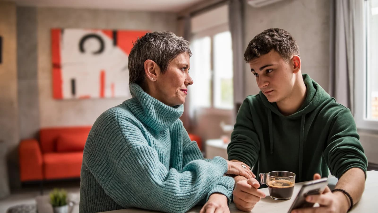 Mother and teenage son having a serious supportive conversation at home about next steps in care