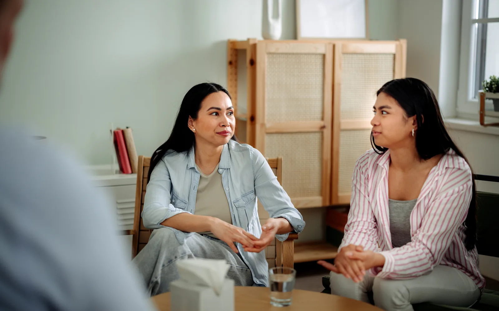 Parent and teen in a family therapy conversation with a clinician.