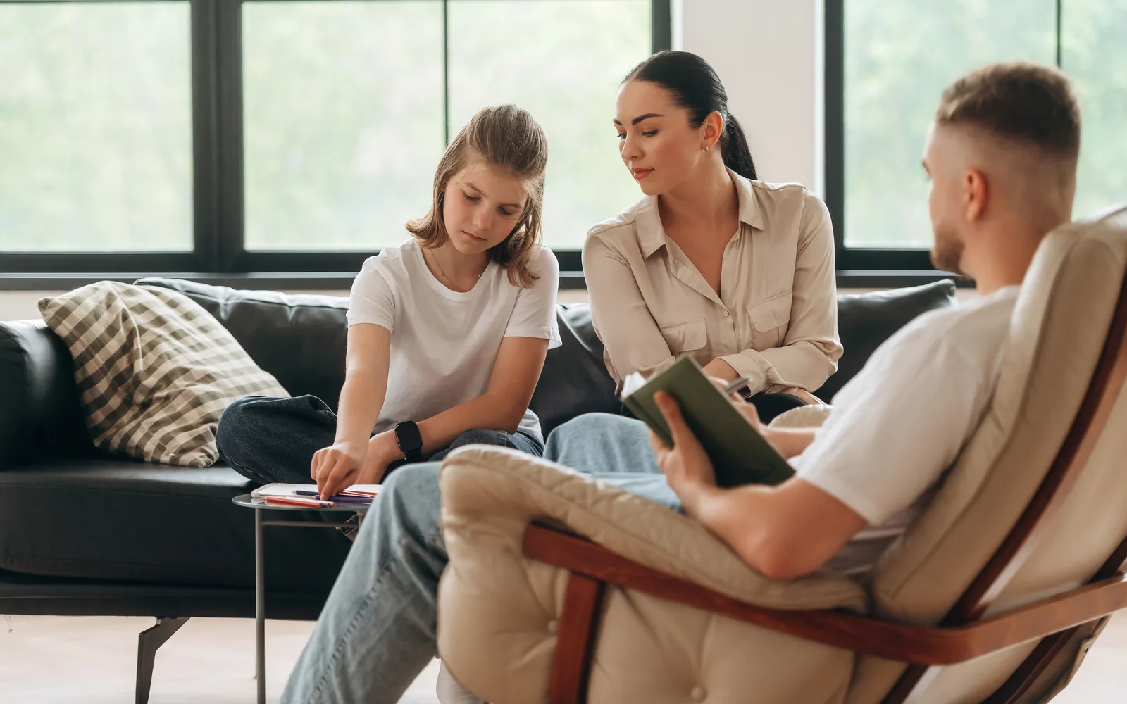 Teen, parent, and clinician sitting together during a family therapy session.
