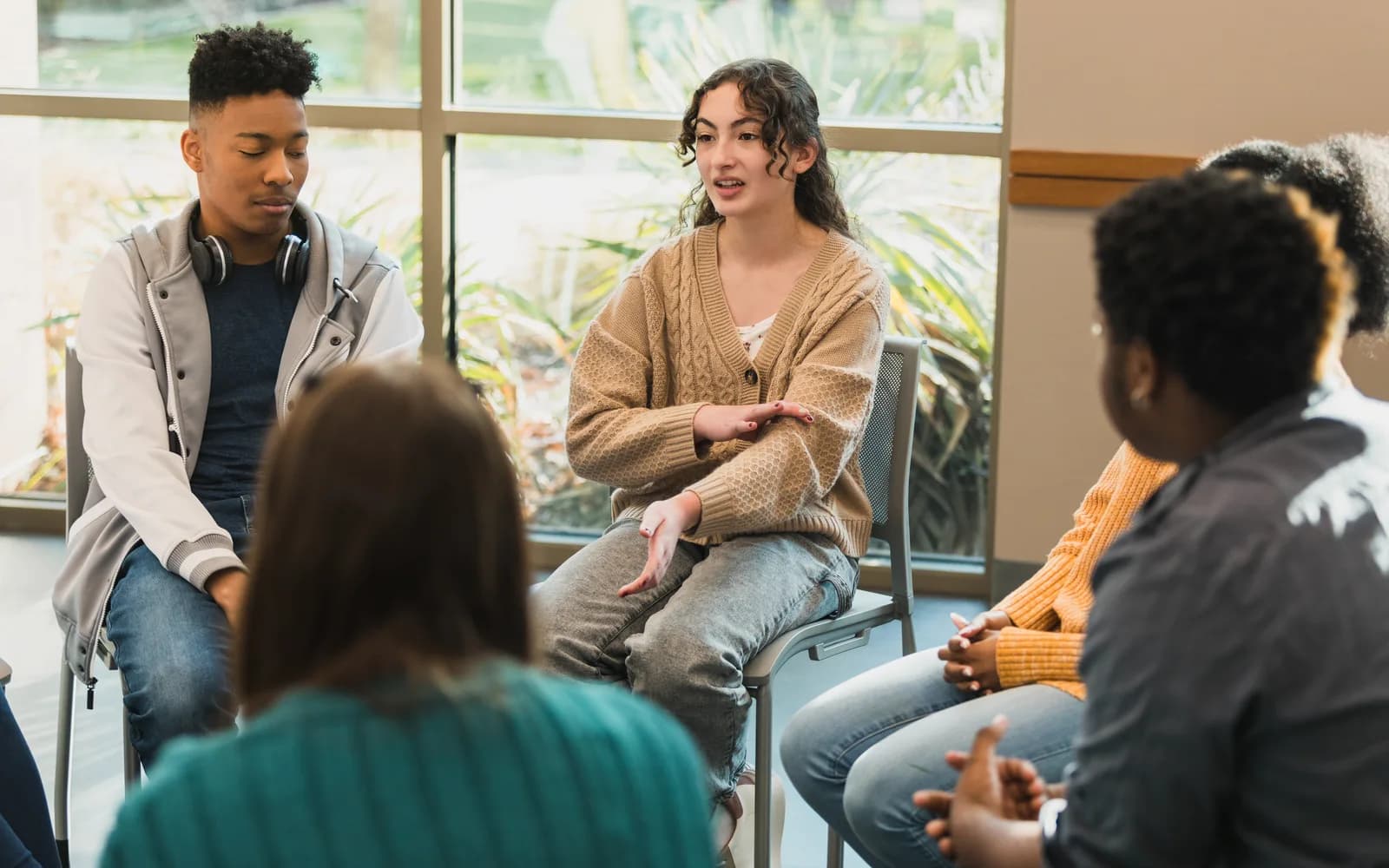 Teens sitting in a facilitated group therapy session.