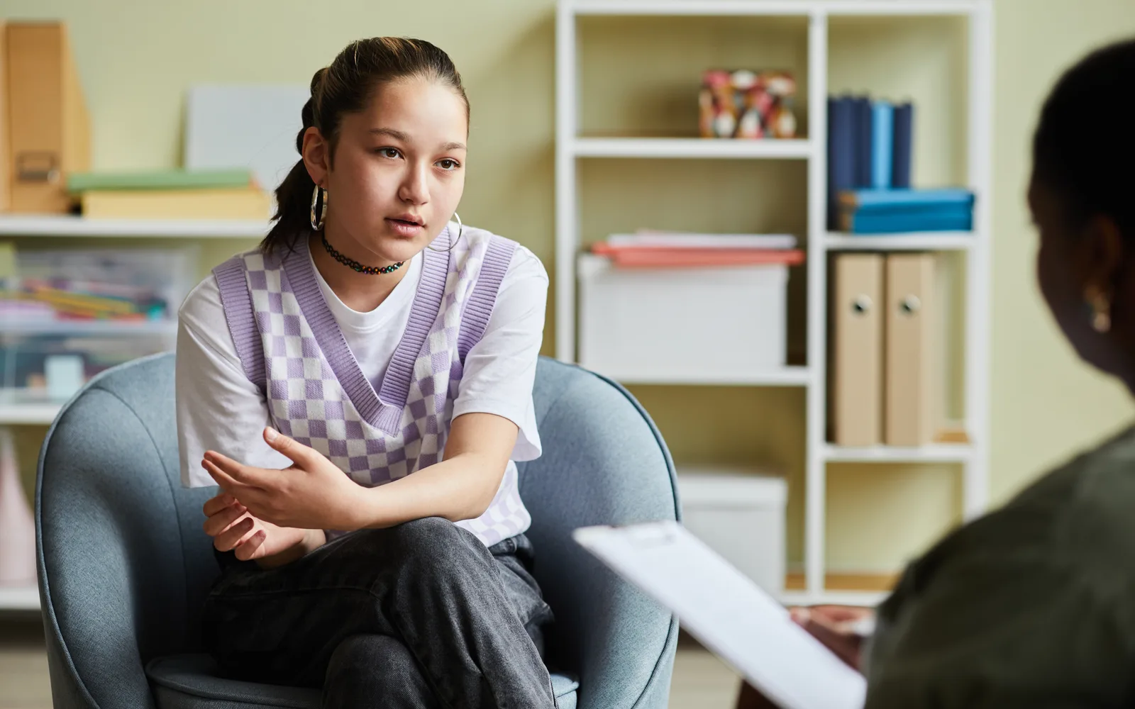 Teen meeting individually with a therapist in a quiet clinical office.