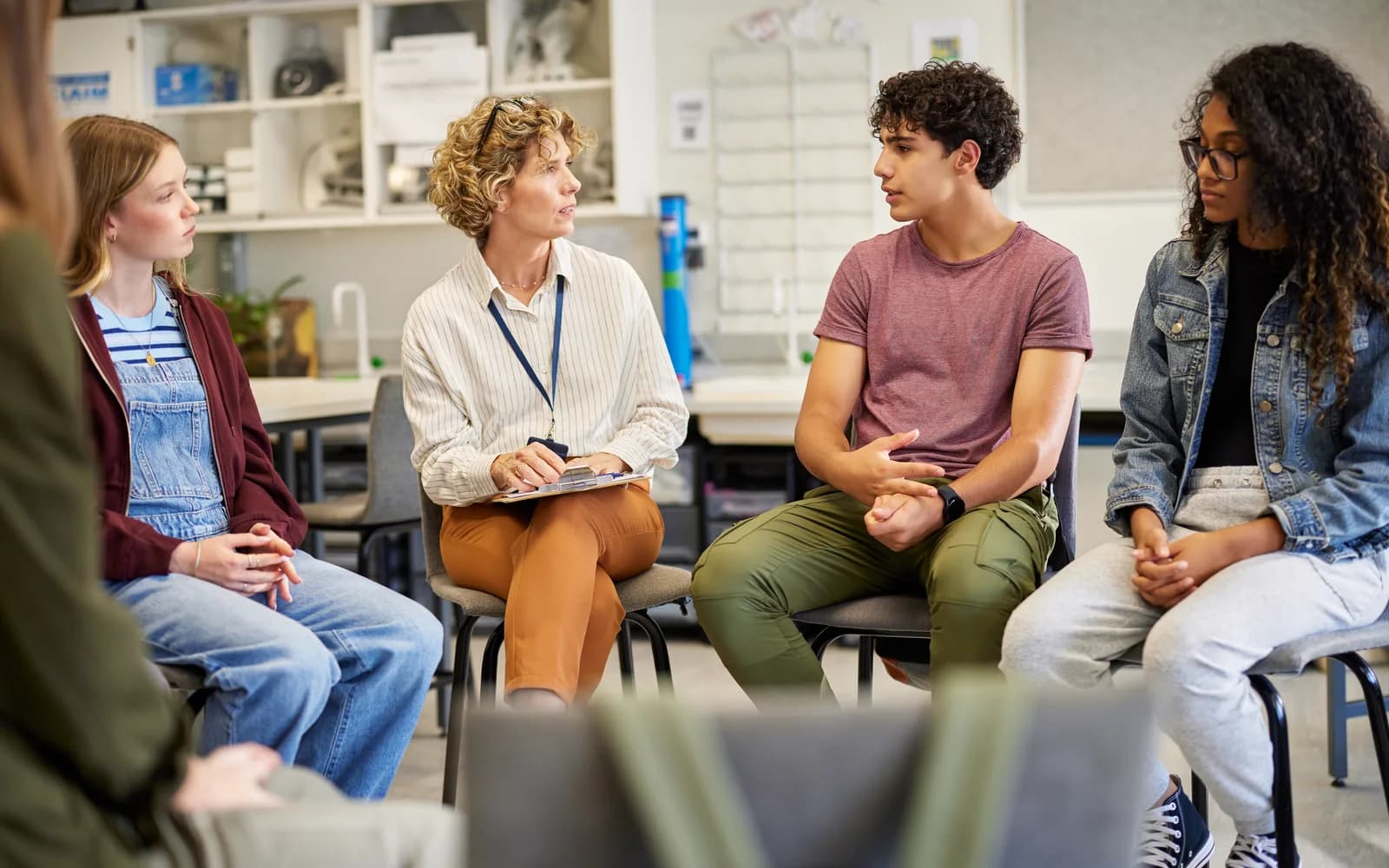 Clinician leading a group discussion with teenagers in a supportive treatment setting.